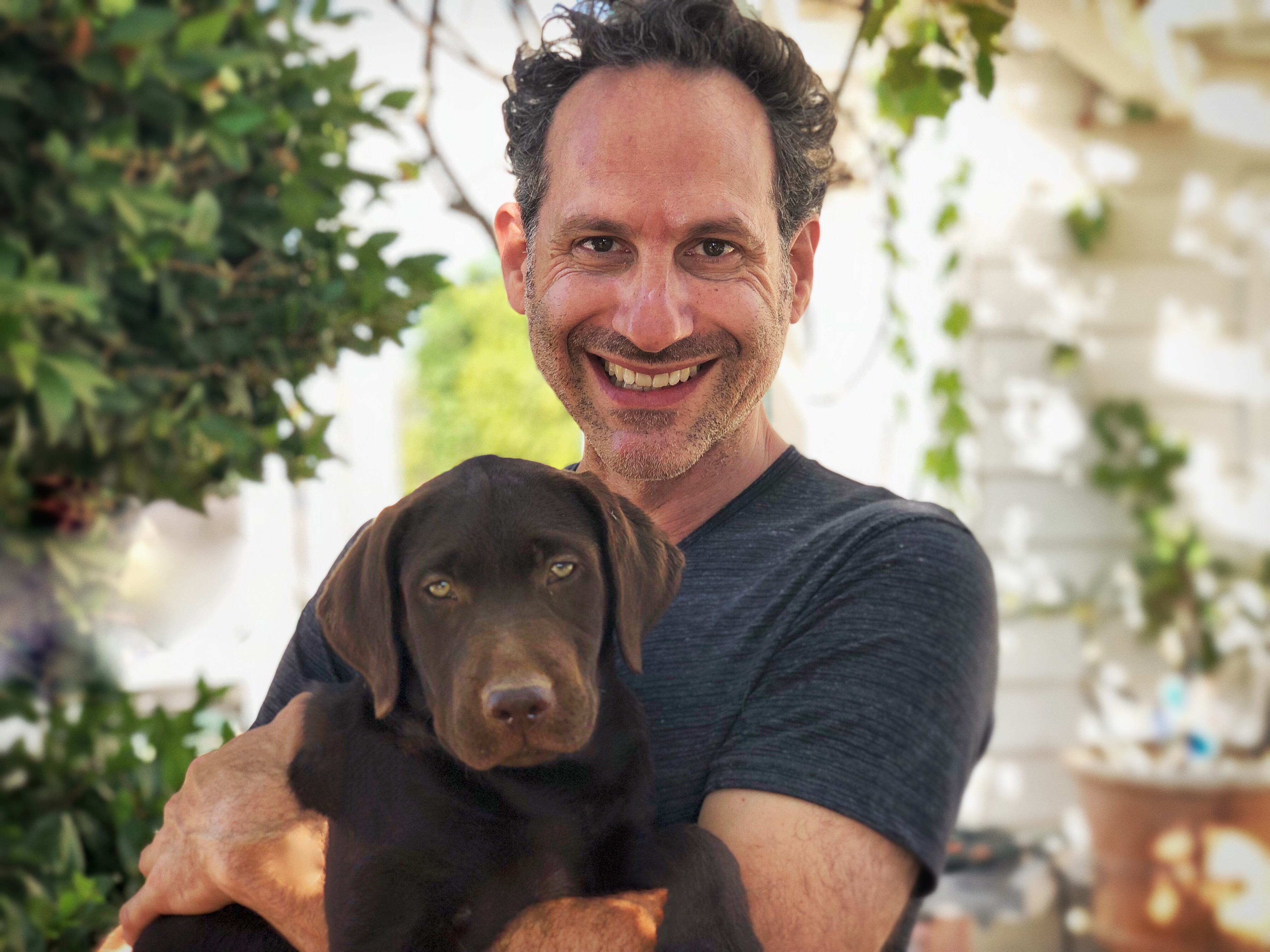 Steven with a chocolate lab puppy, garden